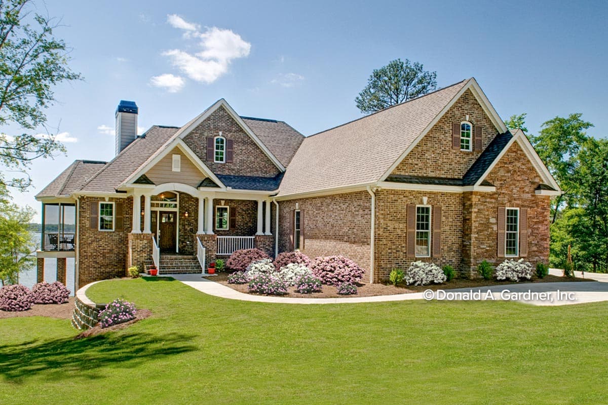 House plan exterior with brick facade, two stories, gable roof, front porch, and dormers. Includes a detached screened porch on the side.