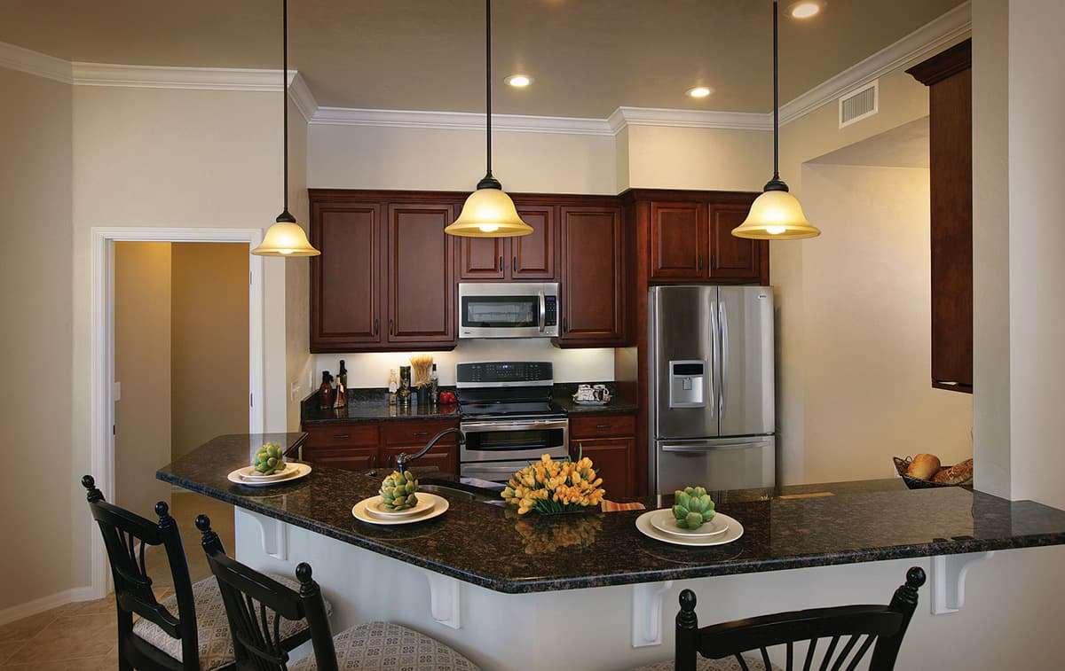 Kitchen featuring dark wood cabinetry, granite countertops, stainless steel appliances, and a breakfast bar with pendant lighting.