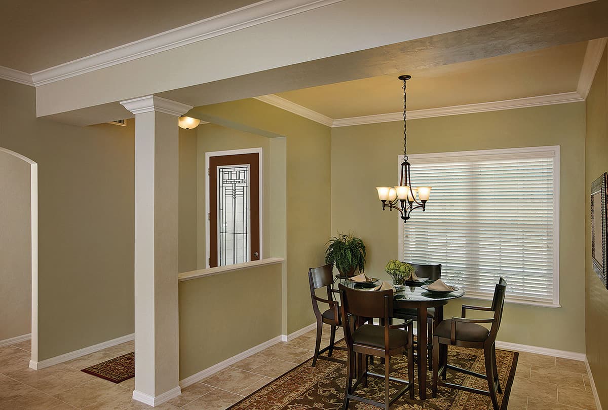 Interior view of a dining area with a round table, chairs, chandelier, and a decorative glass door.