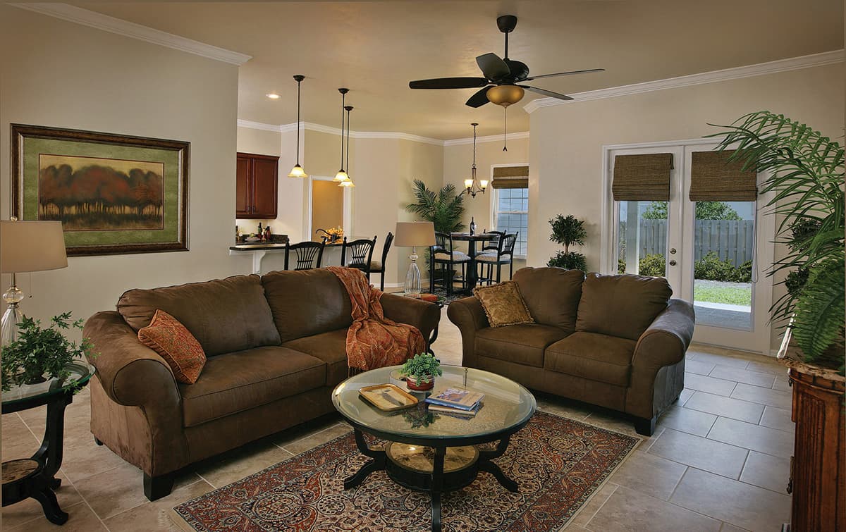 Open concept living area with two sofas, coffee table, ceiling fan, and view into kitchen and dining.