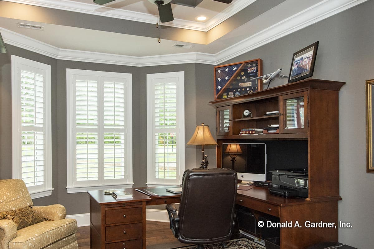 Home office with bay windows, built-in hutch, desk, computer, and chair.