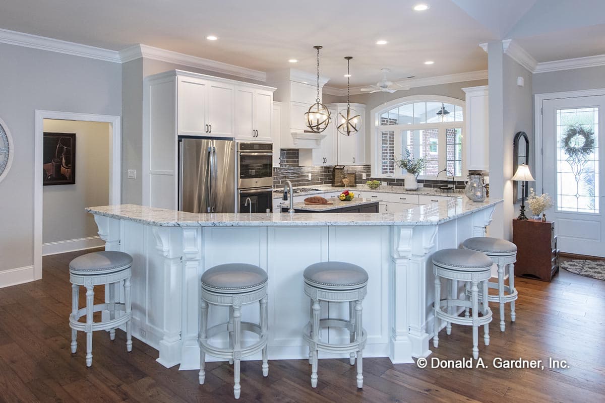 Kitchen interior featuring white cabinetry, stainless steel appliances, granite countertops, and a large curved island with seating.
