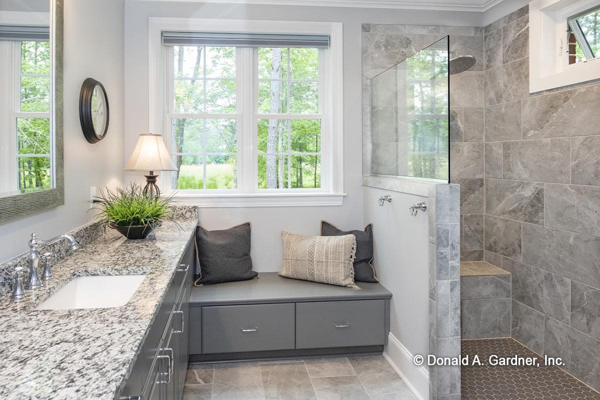 Bathroom interior with vanity, built-in bench seating, and tiled walk-in shower with glass partition.