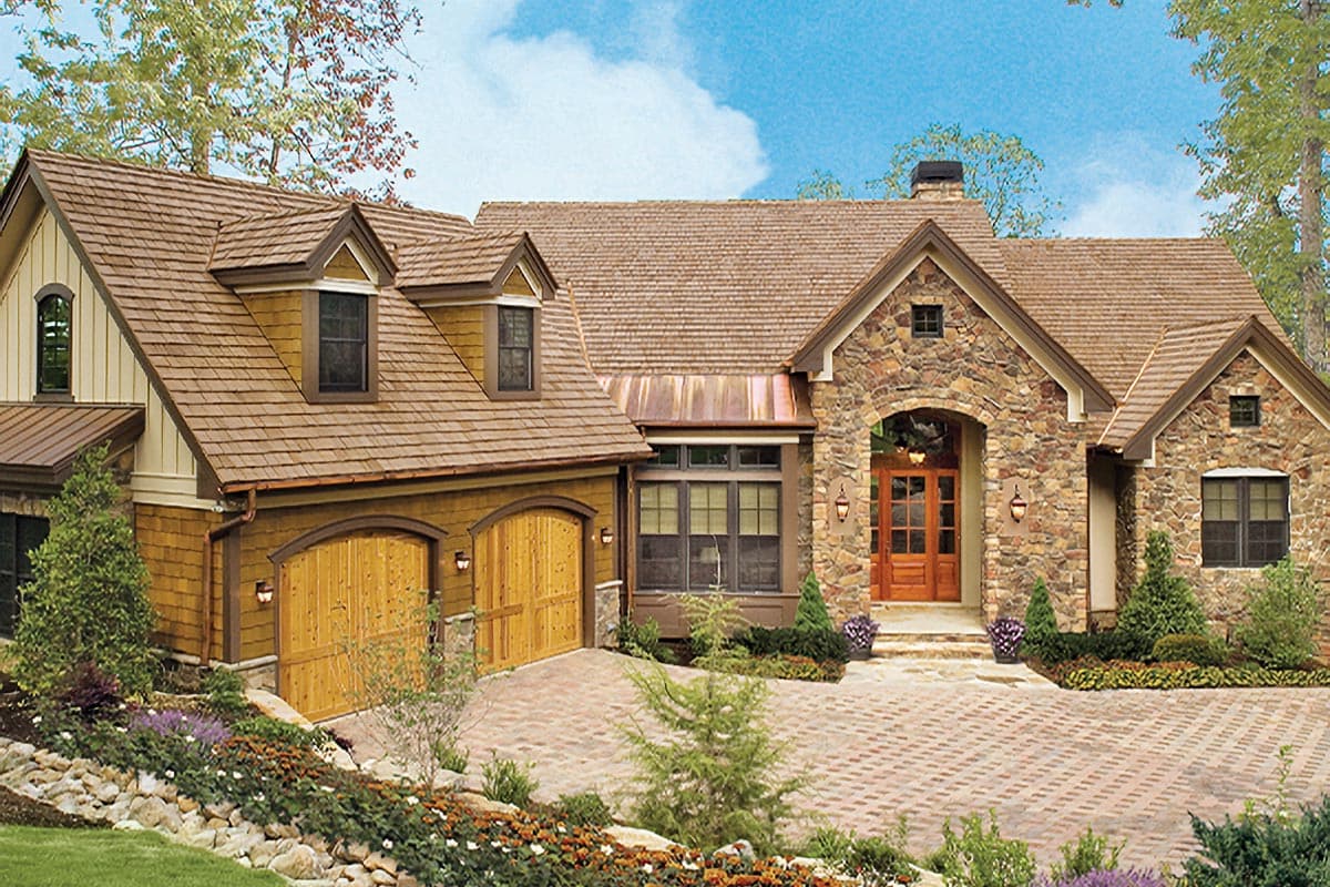 House plan exterior: Stone facade, arched entry, double garage with wooden doors, and dormers.