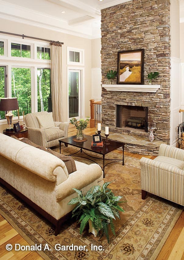 Interior view of a living room with a large stone fireplace, multiple windows, and seating area.