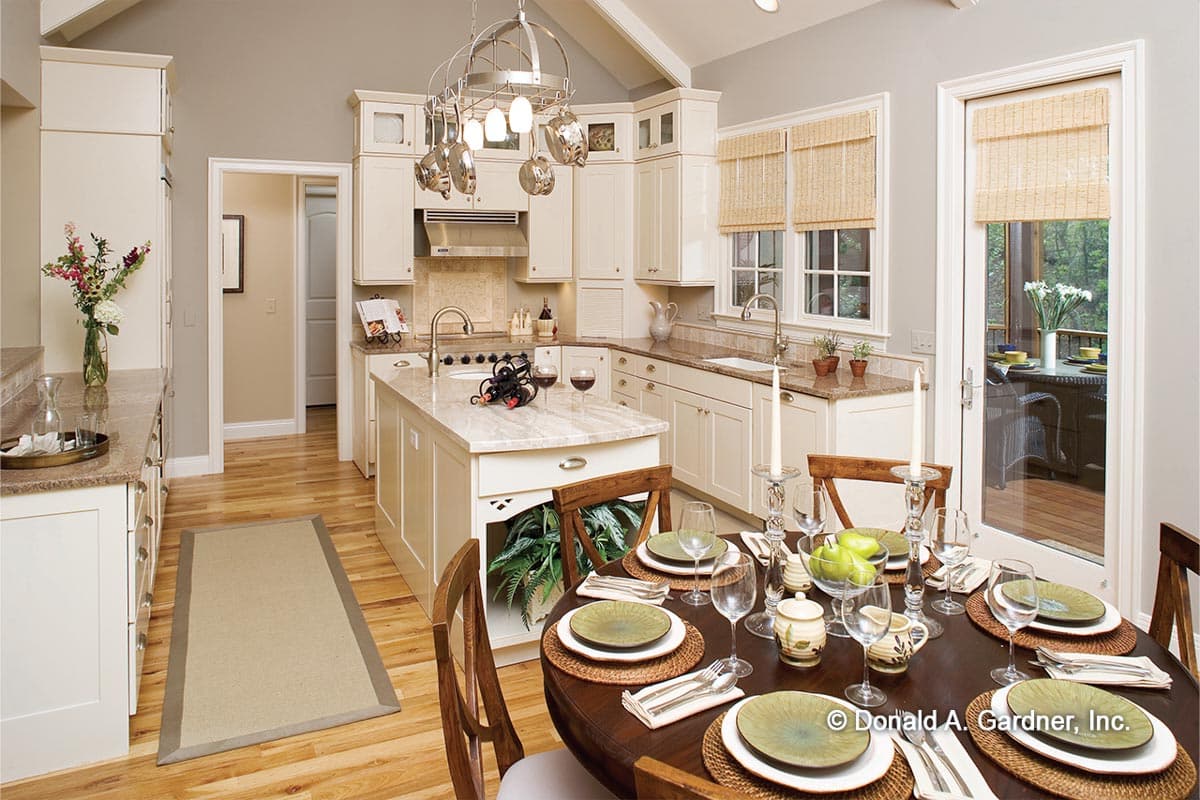 Kitchen with island, vaulted ceiling, and dining area leading to an outdoor patio.