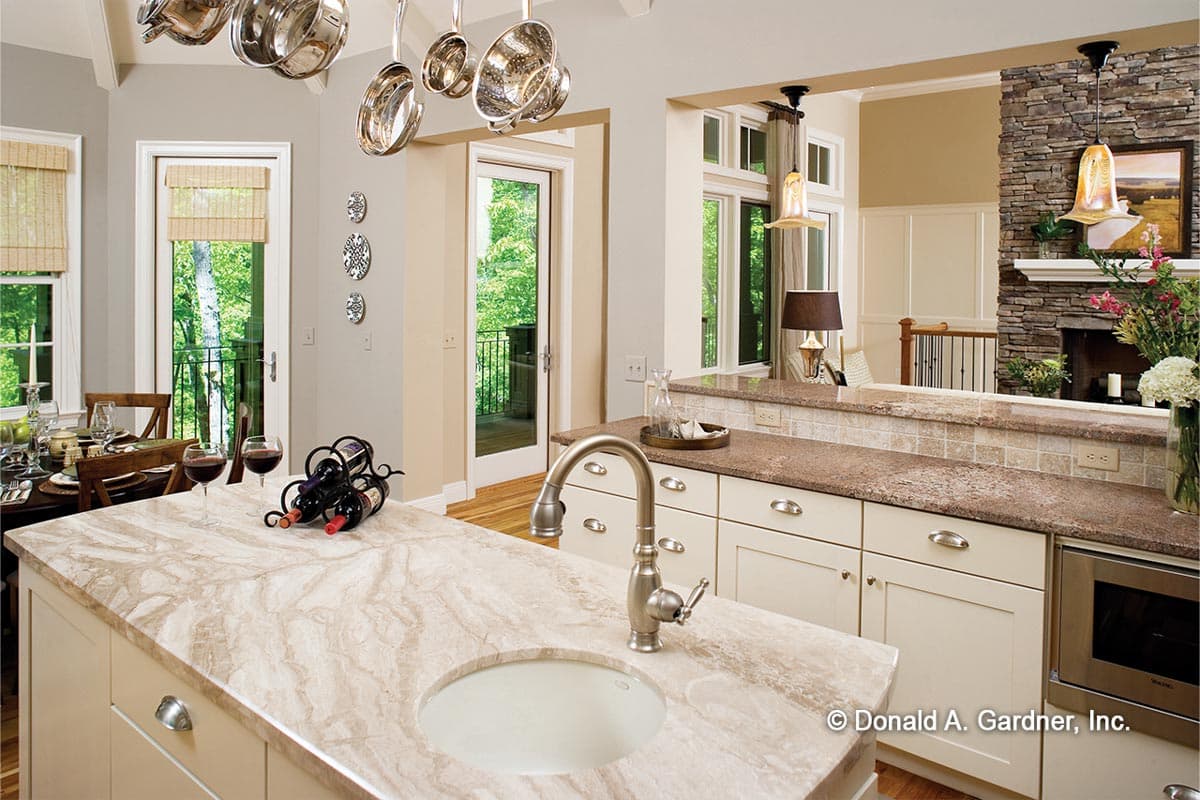 Kitchen island with sink, cream cabinets, stone fireplace, and dining area visible through doorways.