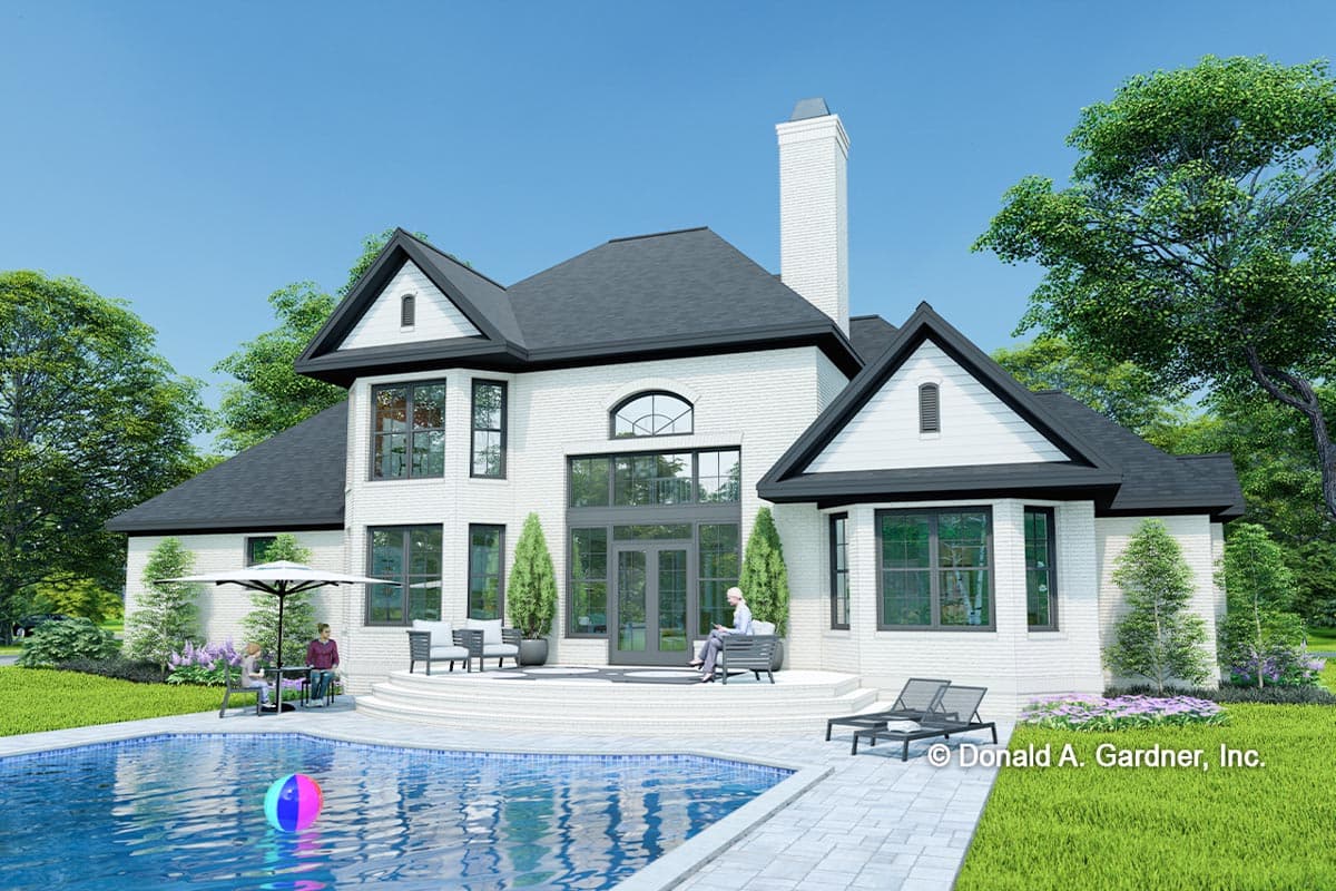 House plan exterior featuring white brick, multiple gables, a large chimney, and a rear patio with pool.