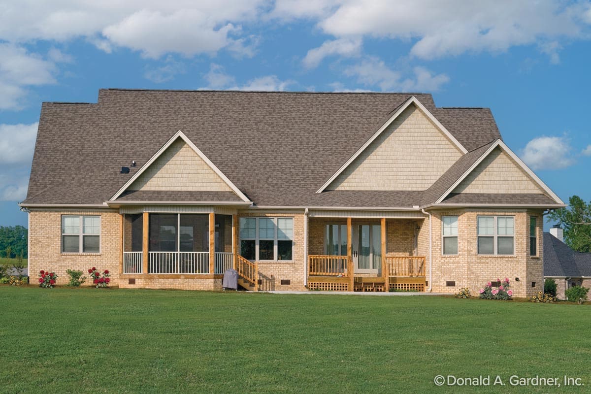 House plan exterior: Two-story brick home with gabled dormers, a screened porch, and multiple wooden decks.