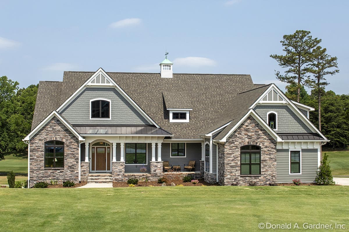 House plan exterior. Craftsman-style home with stone accents, multiple gables, and a front porch. Features dormers and a cupola.