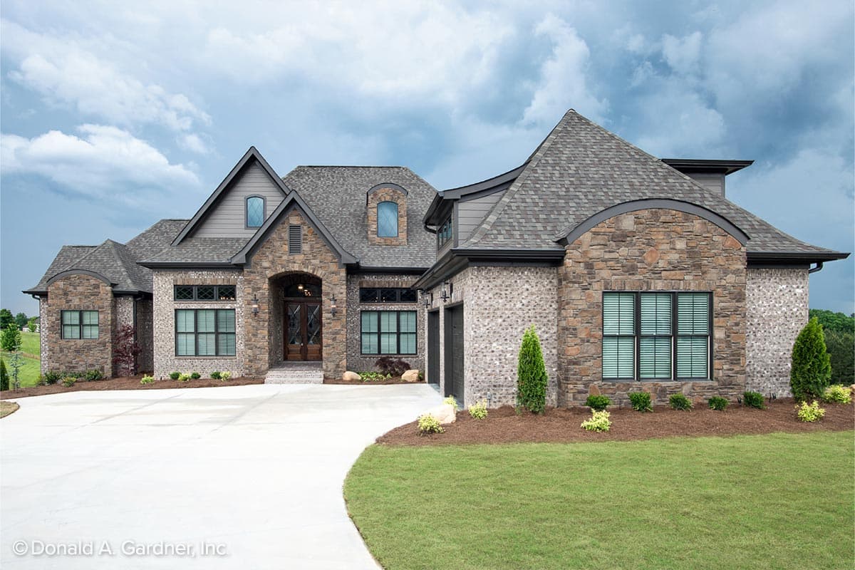 House plan exterior with stone and brick facade, arched entryway, gabled roof, and attached garage. Two stories.