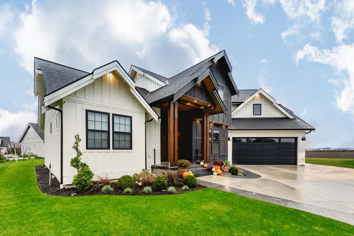 House plan exterior featuring a Modern Farmhouse style, gabled rooflines, board and batten siding, and a dark garage door.