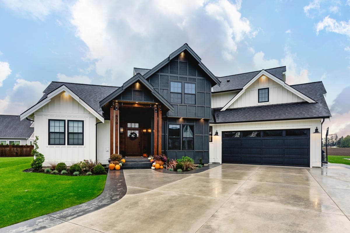House plan exterior. Modern Farmhouse style with two stories, gabled rooflines, a covered porch, and a garage with a dark door.
