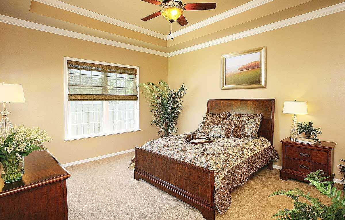 Bedroom with tray ceiling, wooden bed, nightstand, and a large window with blinds.
