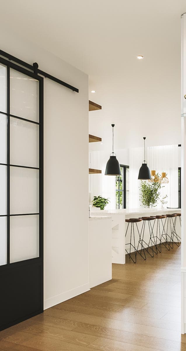 Modern interior with black pendant lights above a kitchen island with bar stools. A sliding glass door and wooden floors add to the design.