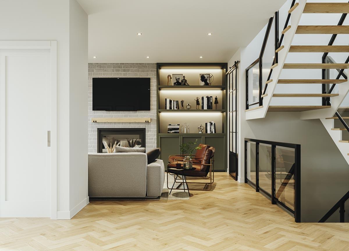 Living area with fireplace, built-in shelving, and stairs with glass railings. Herringbone wood floor.