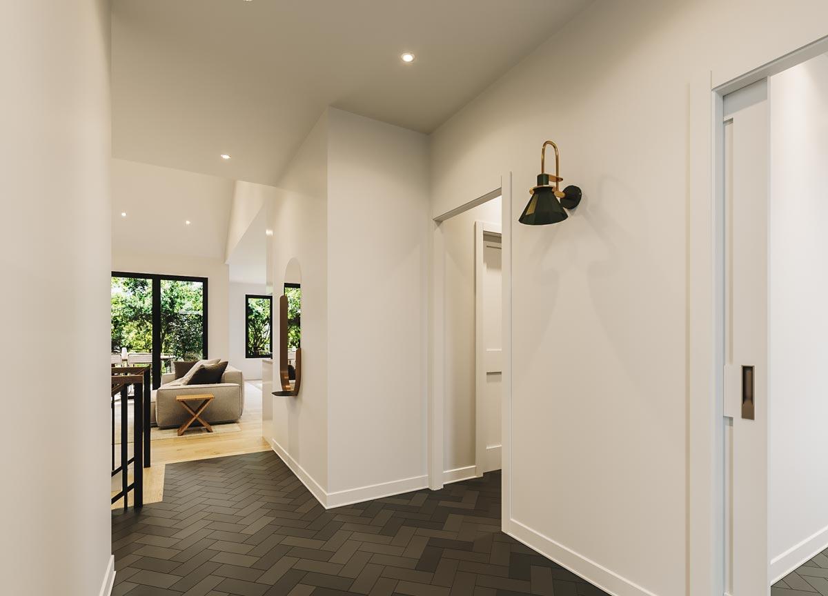 Interior view of a modern house hallway with herringbone tile floor, vaulted ceiling, and open living area visible.