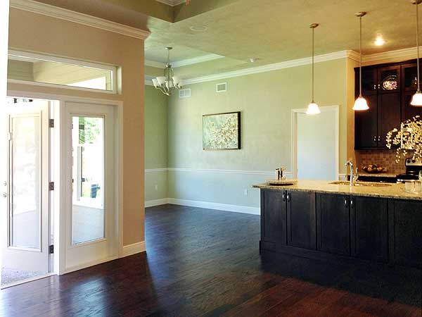 Interior view showing an open layout with a kitchen island, pendant lights, and double doors leading outside.