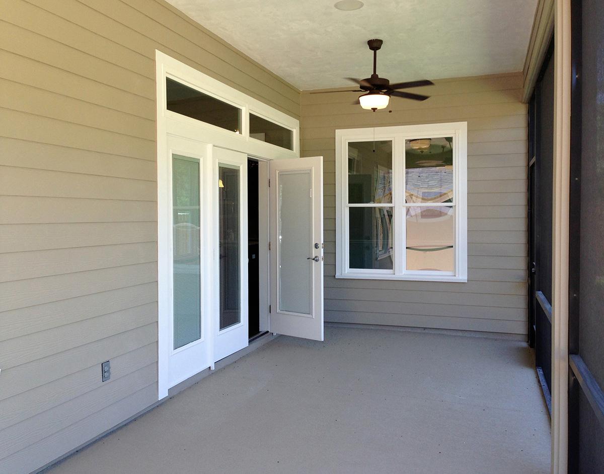 Covered porch with french doors, a double window, and a ceiling fan.
