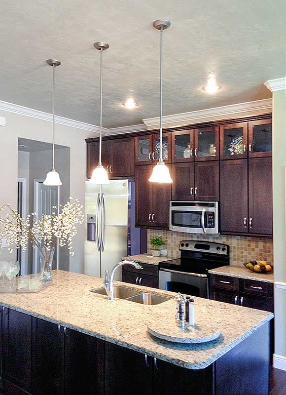 Kitchen with island, granite countertops, dark wood cabinets, stainless steel appliances, and pendant lighting.