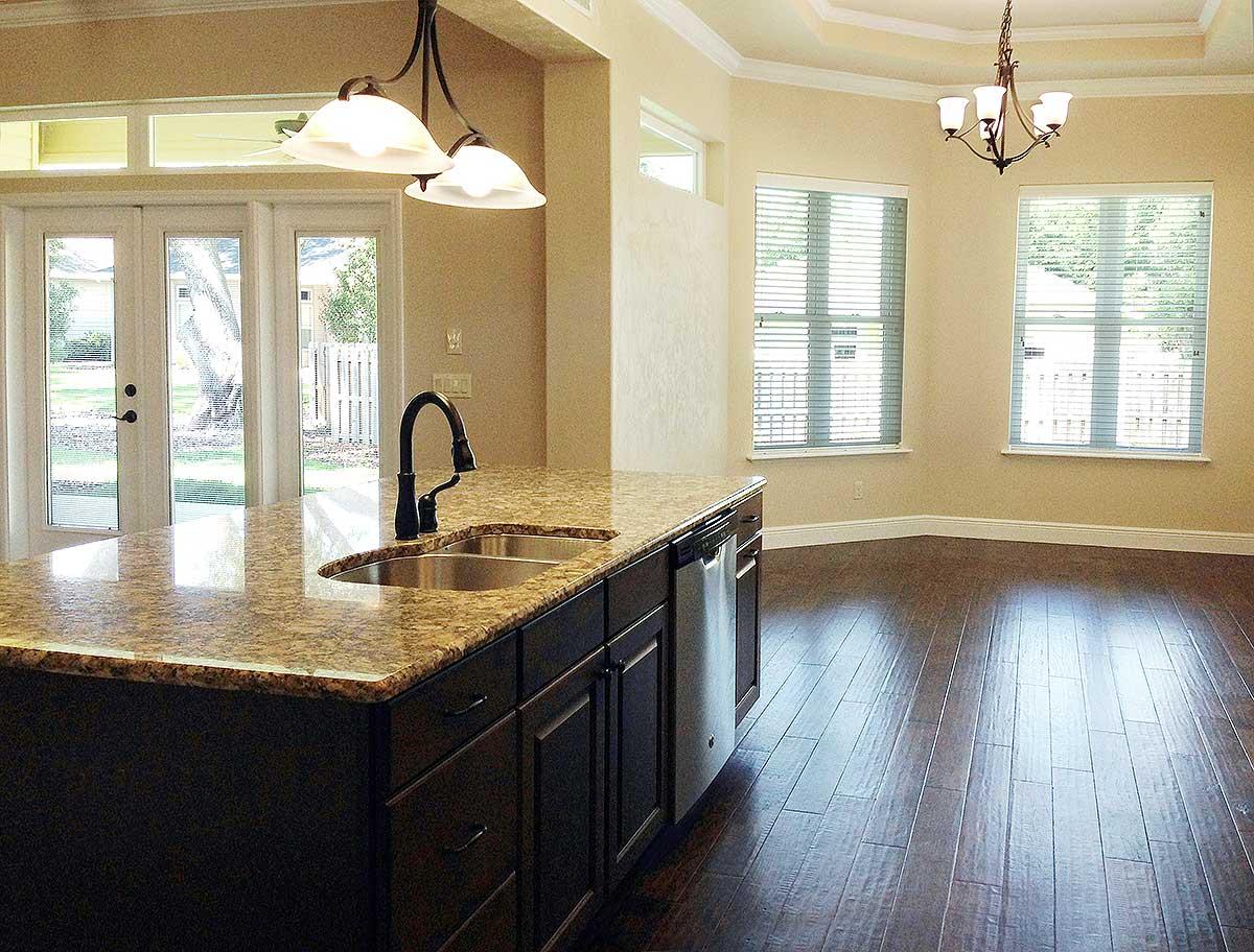 Kitchen island with sink and dishwasher, view to dining area with windows and double doors to exterior.