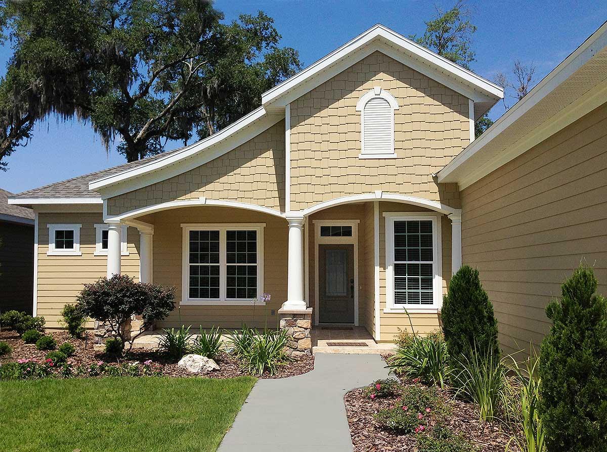 House plan exterior of a one-story home with arched entry, shake siding, gables, and multiple windows.