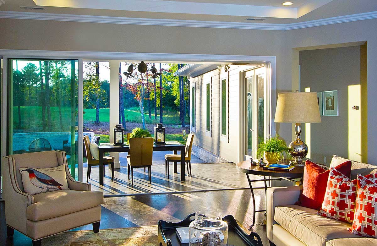 Open concept living area with dining table, large windows, and access to covered patio with golf course view.