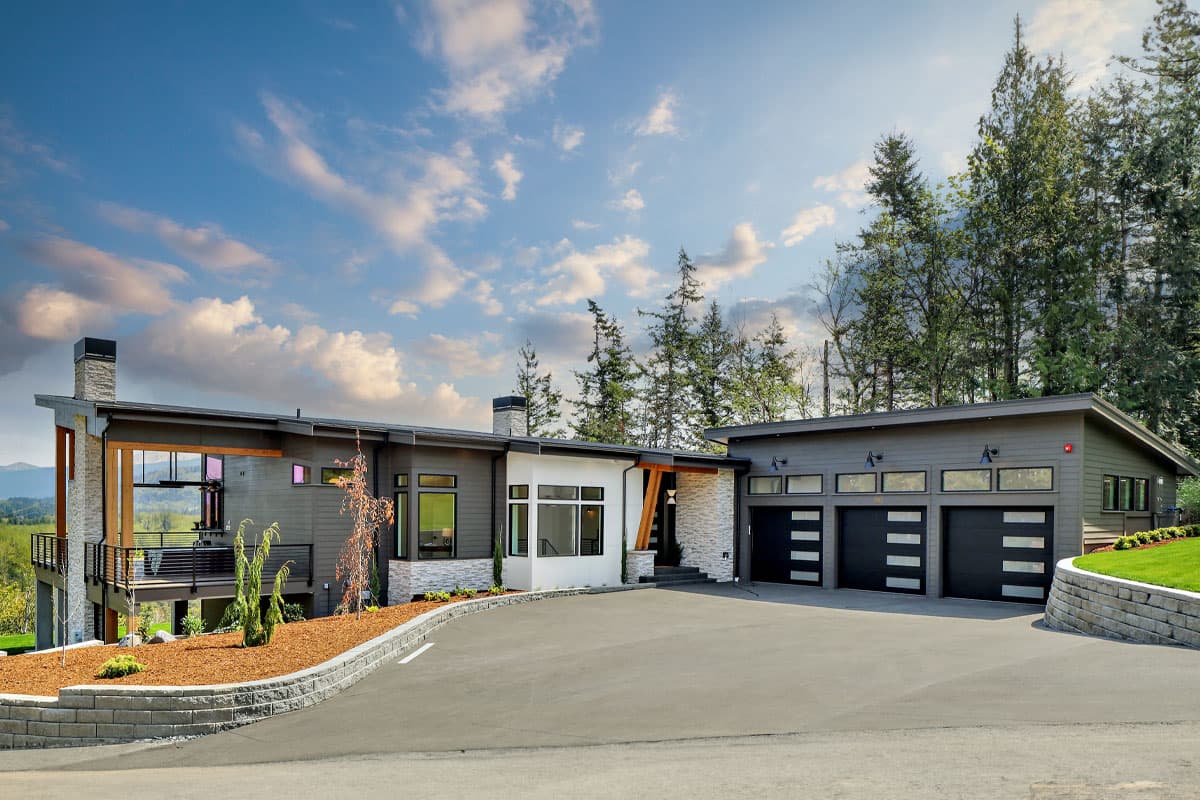 House plan exterior. Modern style with one story, flat rooflines, large windows, and a three-car garage. Stone and wood accents.