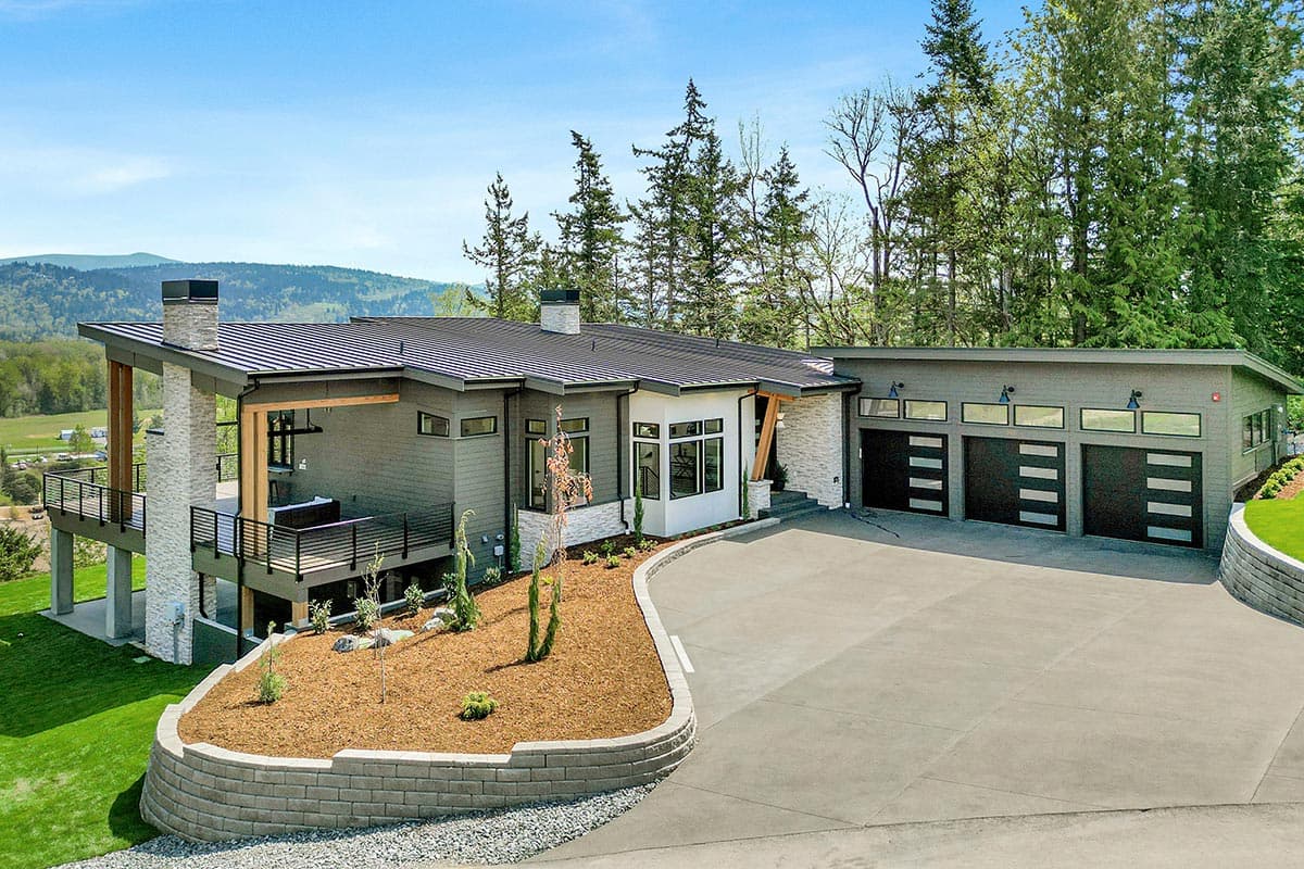 Modern house plan exterior with a low-pitched roof, large deck, stone accents, and a three-car garage with modern doors.