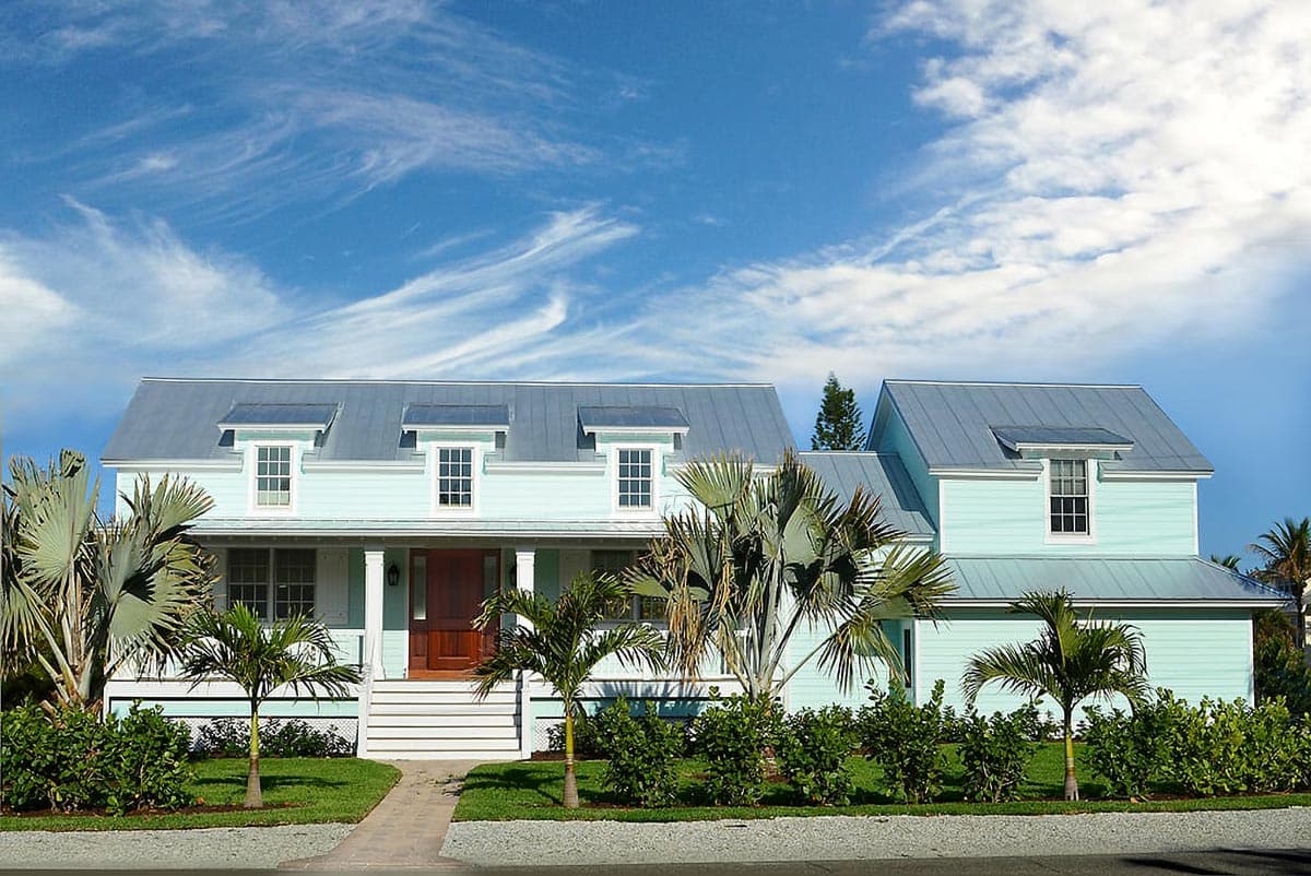 House plan exterior: Two-story light blue coastal style home with metal roof, dormers, and covered front porch.