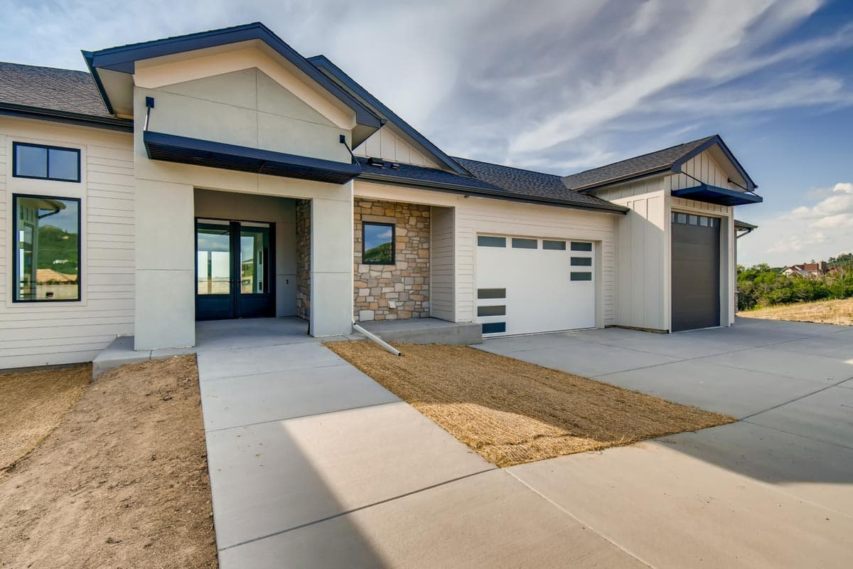 House plan exterior: Modern one-story home with stone accents, covered entryway, large windows, and a three-car garage.