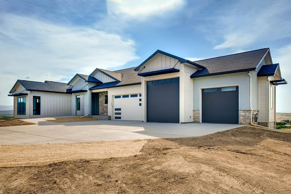 Modern Ranch house plan exterior with a multi-car garage, stucco and stone accents, and dark-trimmed gables.