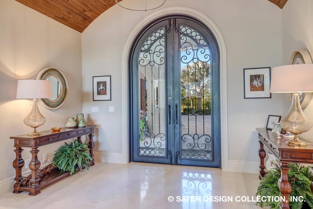 Entryway with arched double doors featuring decorative metalwork and view of palm trees. Wood ceiling.