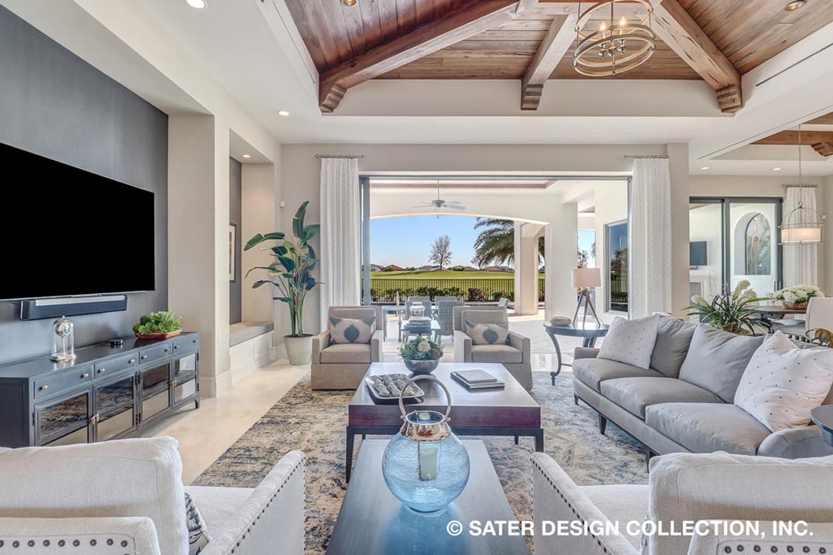 Living room with vaulted wood beam ceiling, fireplace, and open access to a patio with pool.