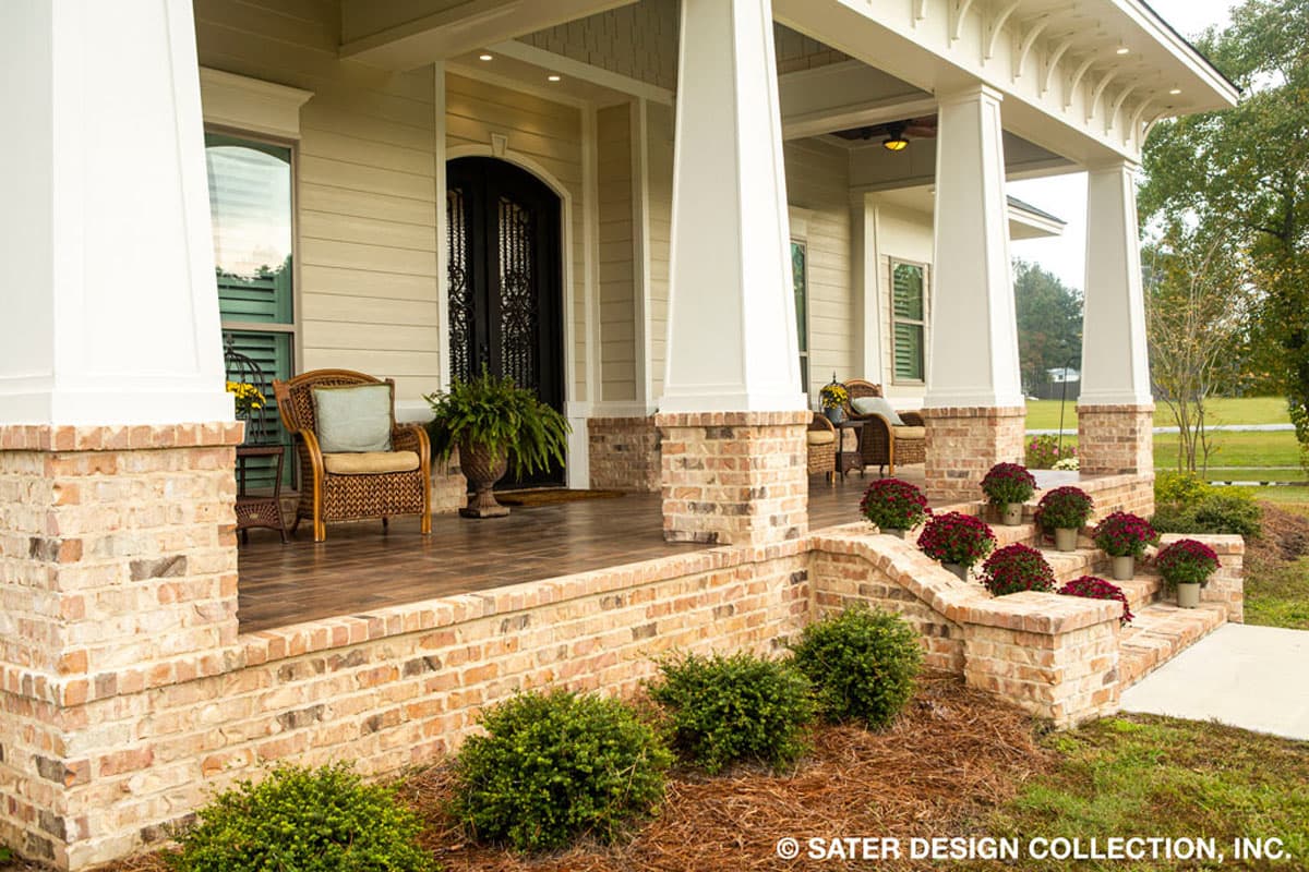 House plan exterior: Southern home with wide covered porch supported by brick and white columns, double entry doors, and tiered brick steps.