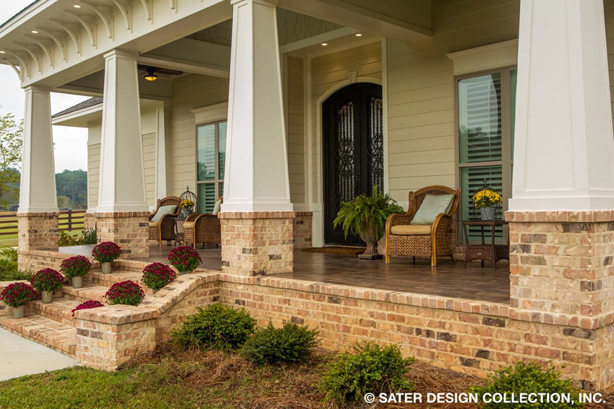 House plan exterior with large brick porch, arch-top double doors, multiple windows, and white columns with decorative brackets.