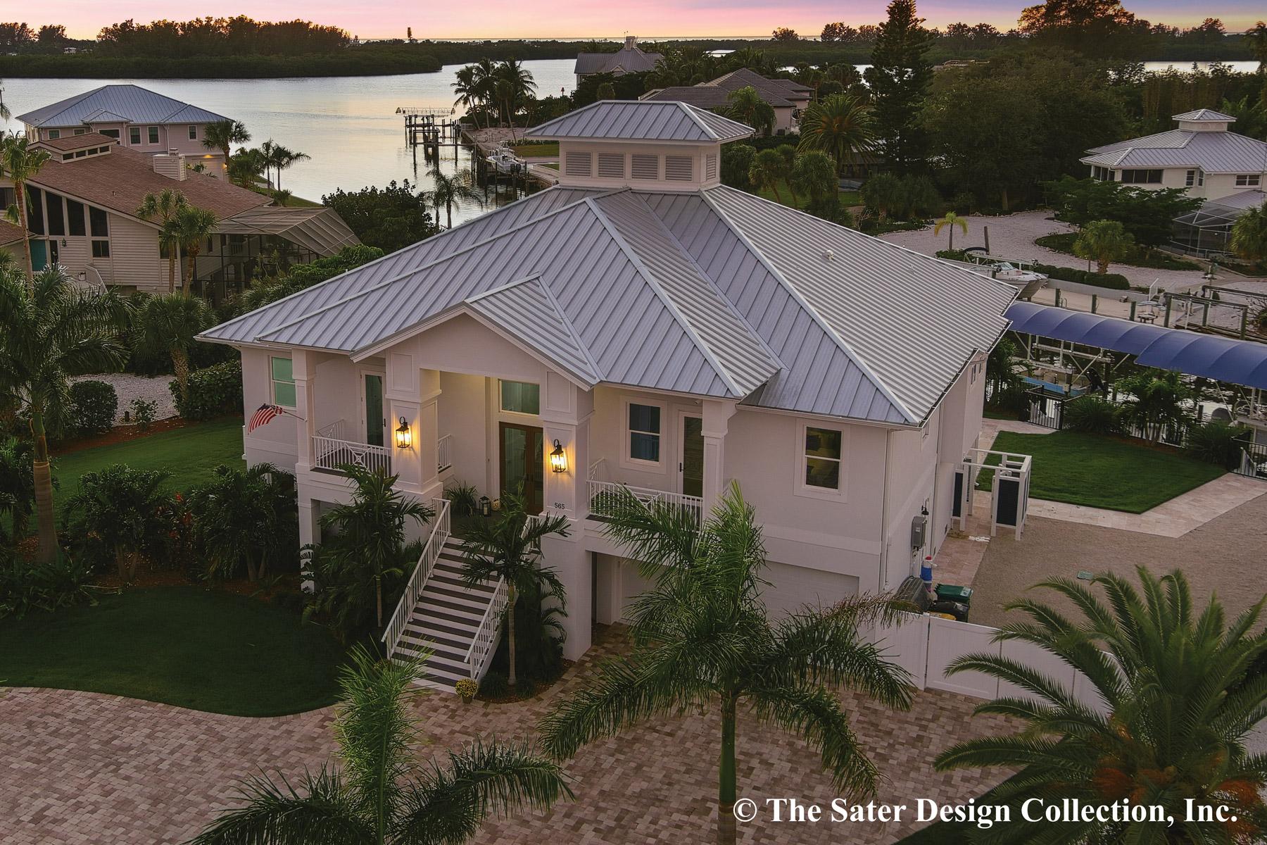 House plan exterior. Two-story coastal-style home with a metal roof, cupola, and elevated porch entry. Features a garage and waterside view.
