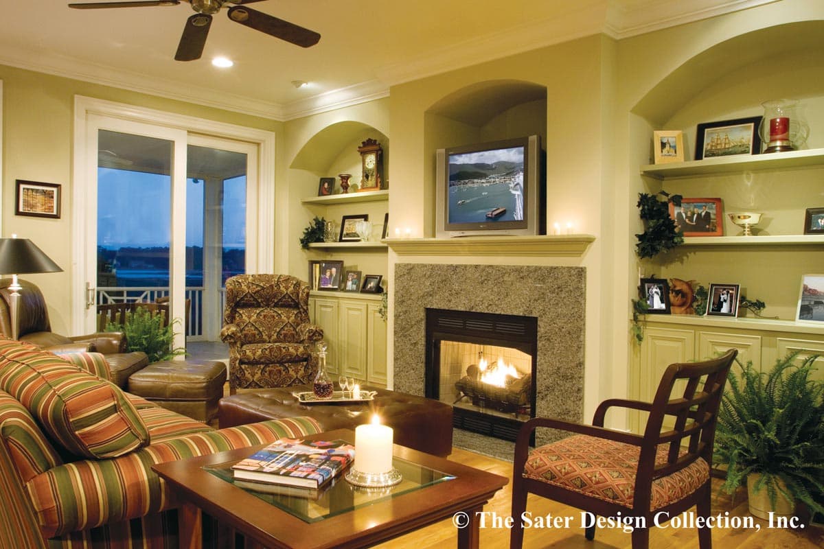 Living room with fireplace, built-in shelving, entertainment center, sliding glass doors, and ceiling fan.