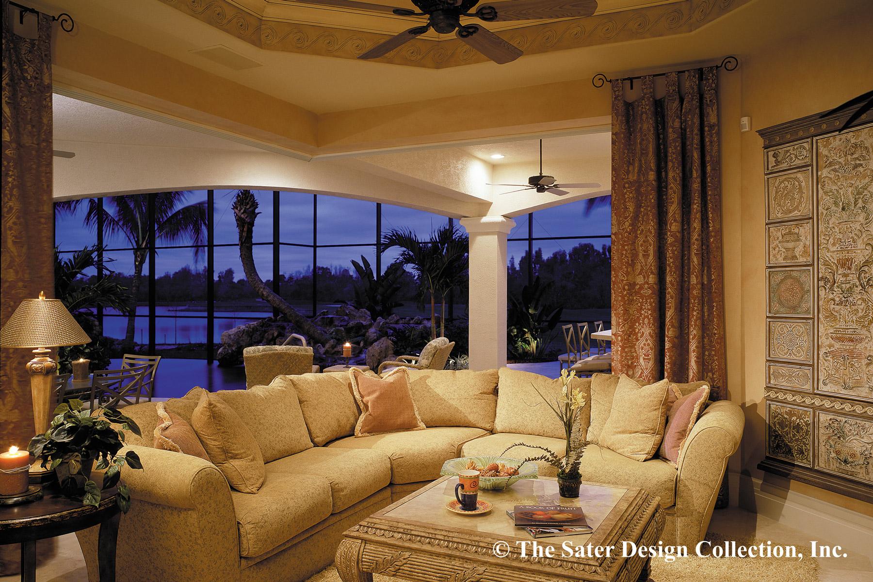 Living room with sectional sofa, ornate coffee table, and large windows overlooking a tropical landscape at dusk.