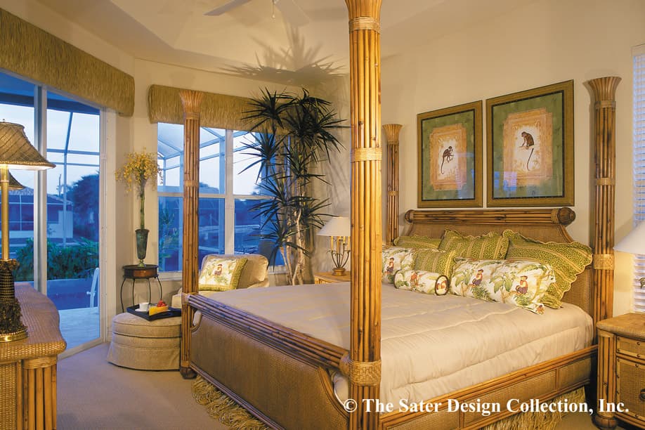 Primary bedroom with a four-poster rattan bed, wall art, and sliding glass doors to a screened patio.