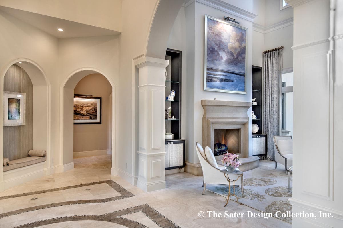 Interior view of a grand entryway with arched openings, a stone fireplace, and a built-in display cabinet.