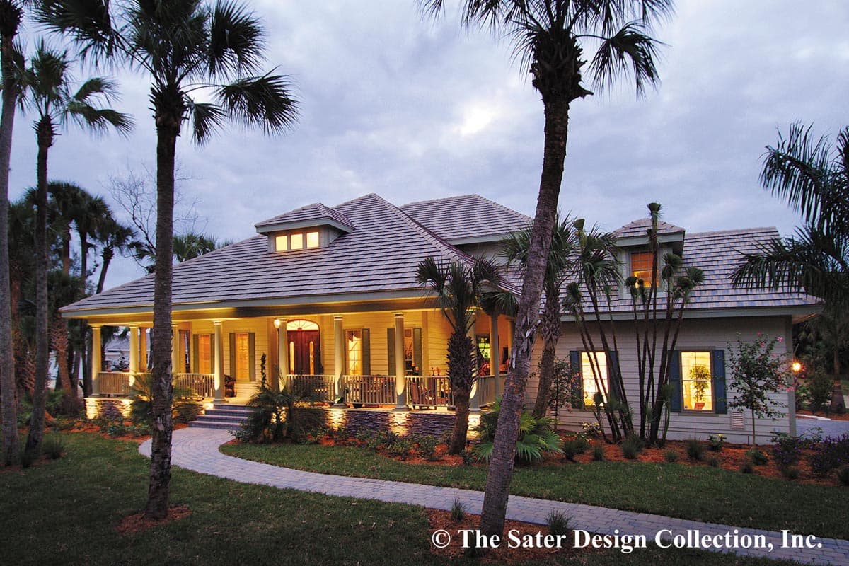 House plan exterior featuring a low-pitched roof, covered porch with columns, and dormers. The house is surrounded by palm trees and landscaping.