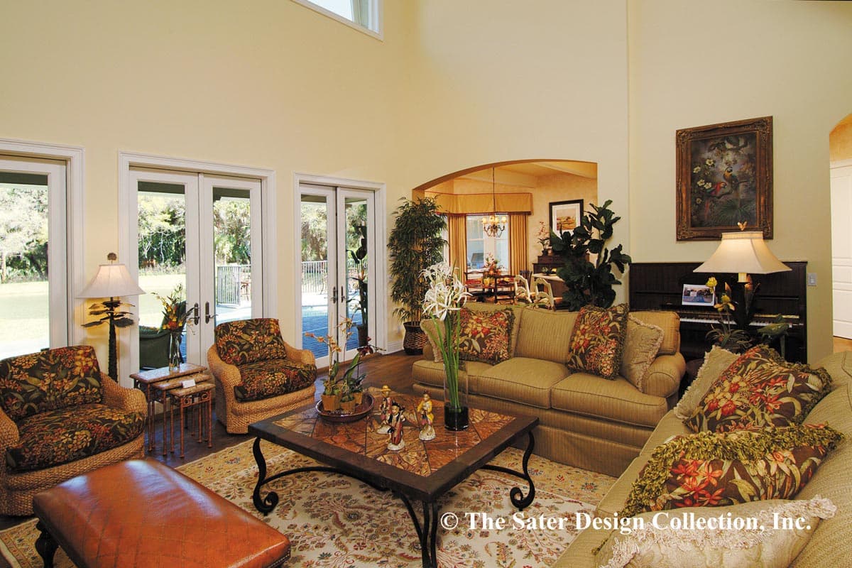 Living room with vaulted ceiling, large glass doors opening to patio, and an adjoining dining area with a chandelier.