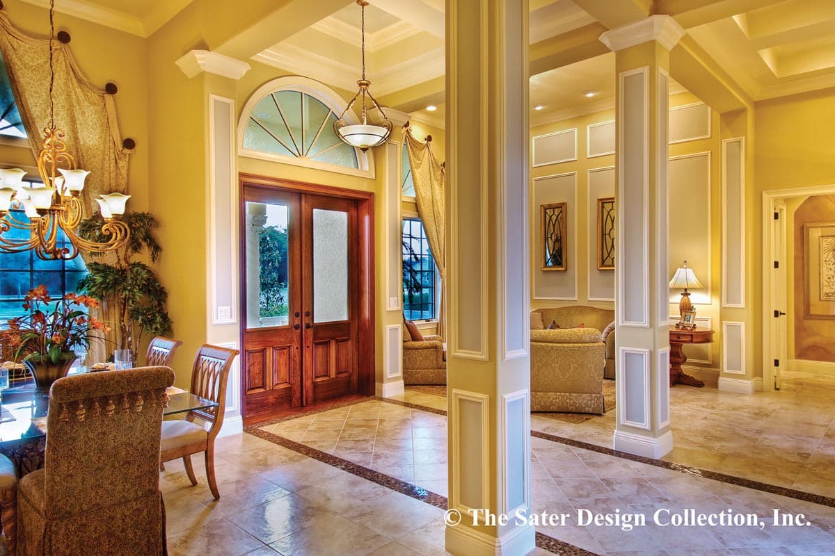 Interior view of foyer with double doors, arched transom window, coffered ceiling, and decorative columns.