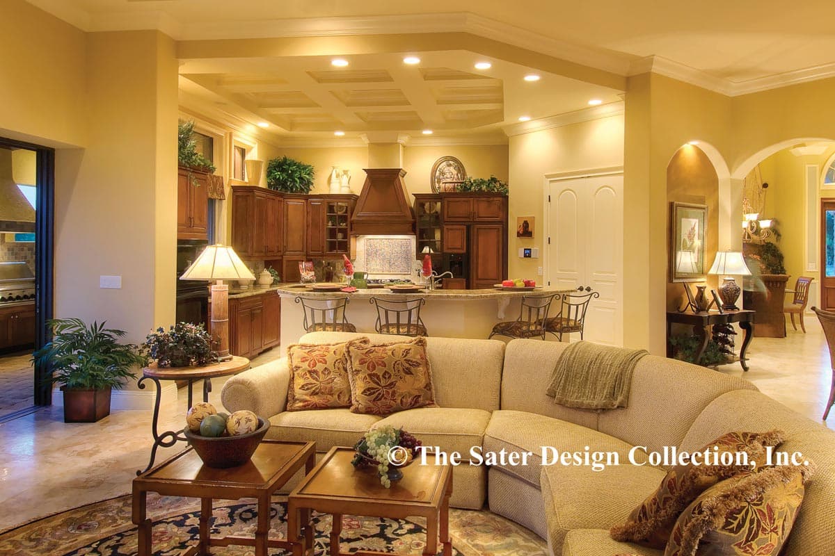 Open-concept living area with kitchen island, coffered ceiling, and curved sectional sofa.