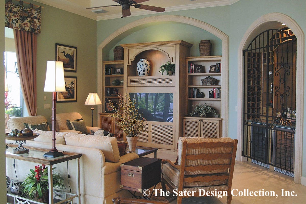Living room with built-in entertainment center, archways, and wine cellar entry with wrought iron gate.