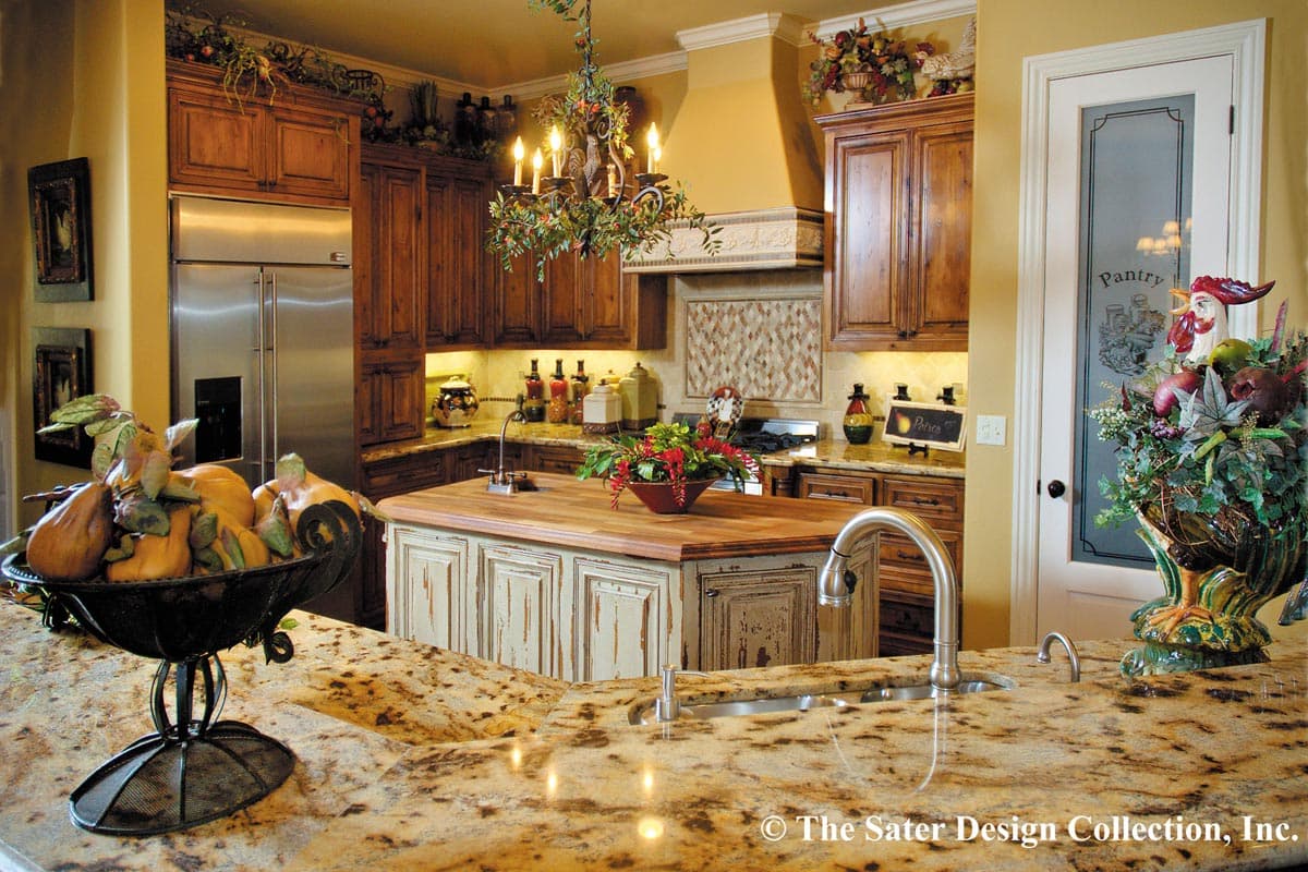 Kitchen interior with distressed island, granite countertops, custom wood cabinetry, stainless steel refrigerator, and pantry door.