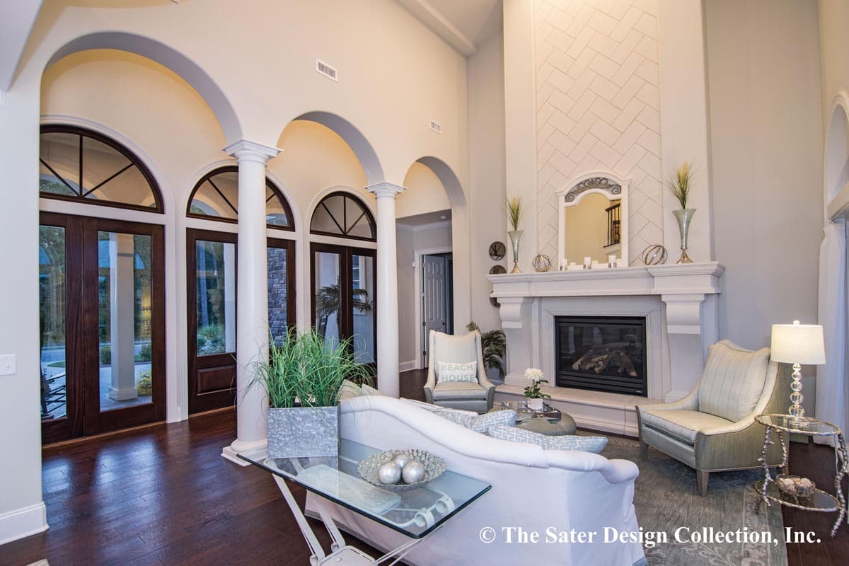 Interior view of a living room with arched doorways, columns, fireplace with ornate mantel, and white sectional sofa.