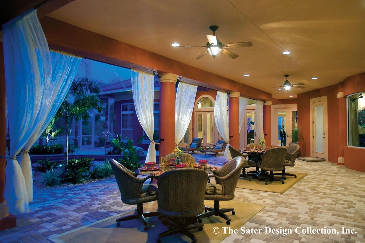 Covered outdoor living space with dining and lounge areas, white sheer curtains, ceiling fans, and Tuscan columns.