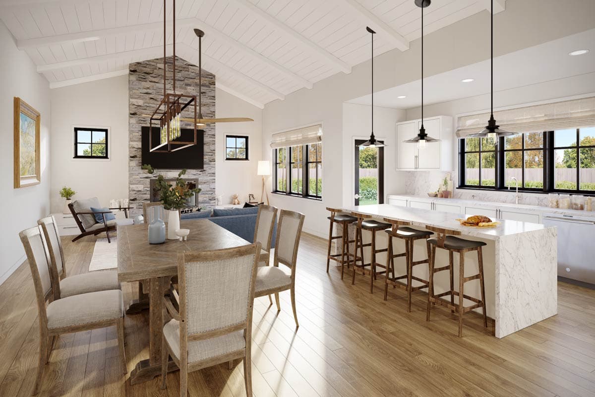 Open concept great room and kitchen with vaulted ceiling, stone fireplace, large island with seating, and dining area.